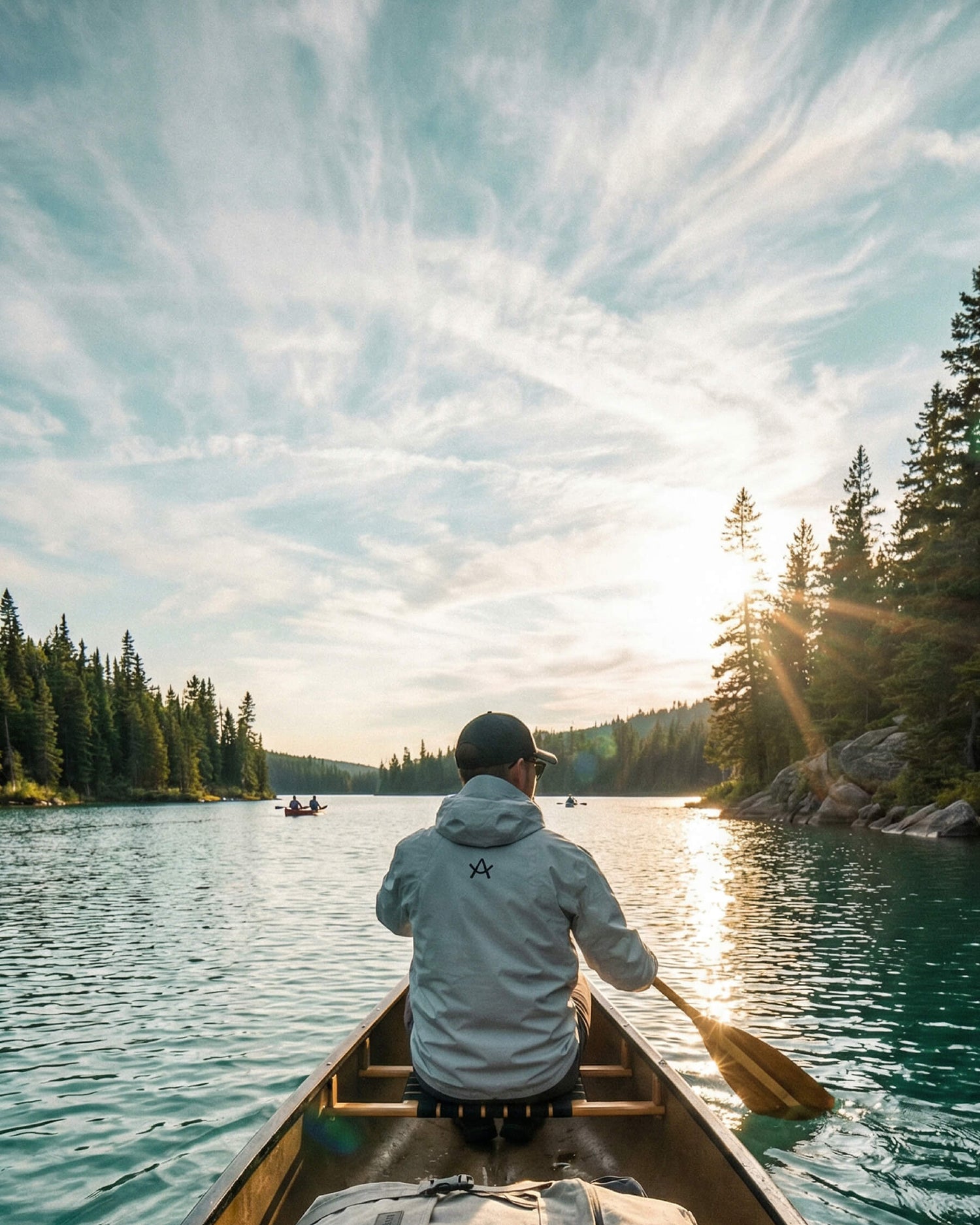 Arksen fractional yacht ownership showing someone paddling along rock and treelined shores with the sun setting. 